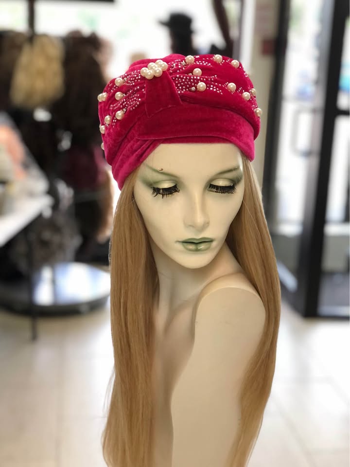 A mannequin wearing a red turban with pearls.