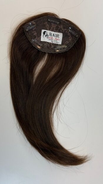 A brown wig with long hair hanging on the wall