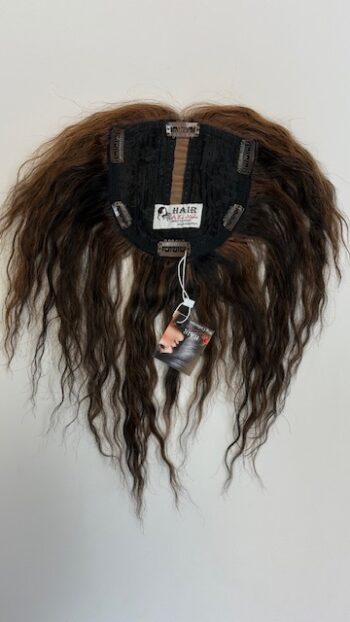 A wig hanging on the wall with tags attached.