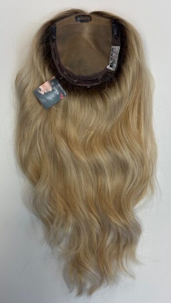 A blonde wig with long hair hanging on the wall.