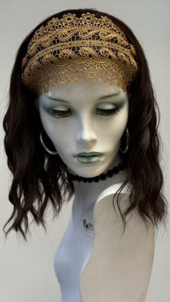 A mannequin wearing a gold headband and earrings.