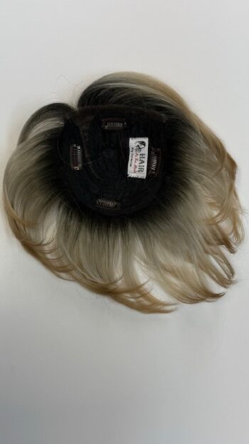 A black and brown wig on top of a white table.