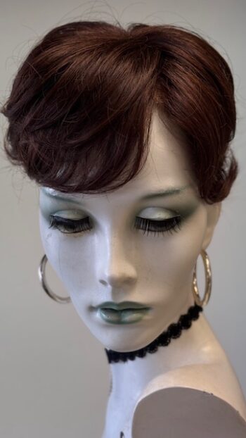 A mannequin with green makeup and black earrings.