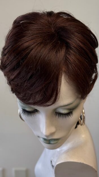 A mannequin head with long eyelashes and a brown hair style.