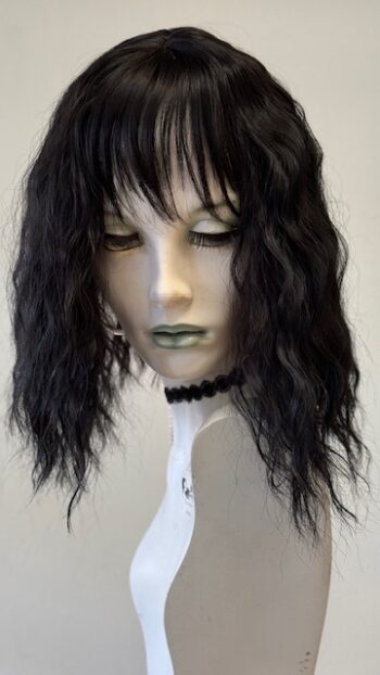 A mannequin head with black hair and green eyes.