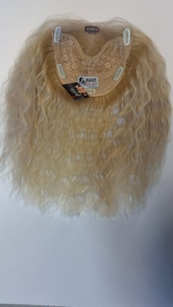 A wig hanging on the wall with a tag.