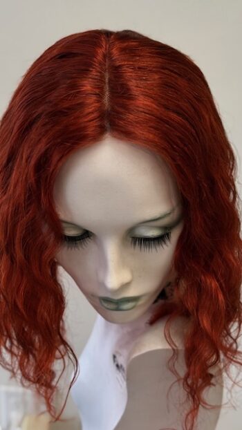 A close up of a doll head with red hair