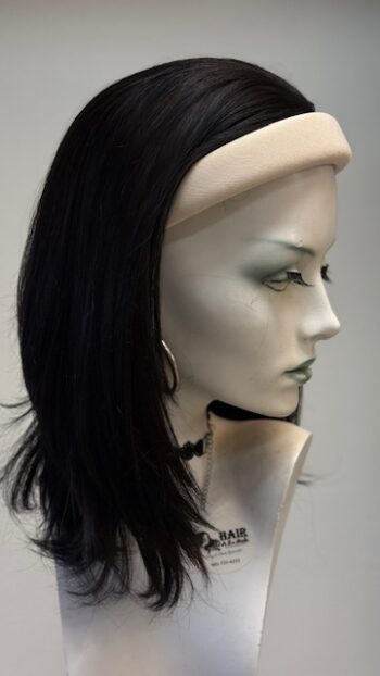 A mannequin head with long black hair and silver earrings.