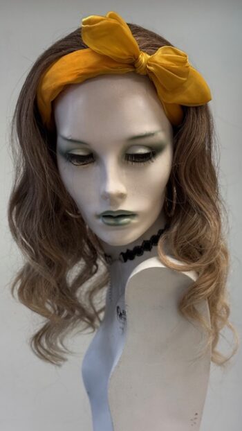 A mannequin wearing a yellow headband and green lipstick.