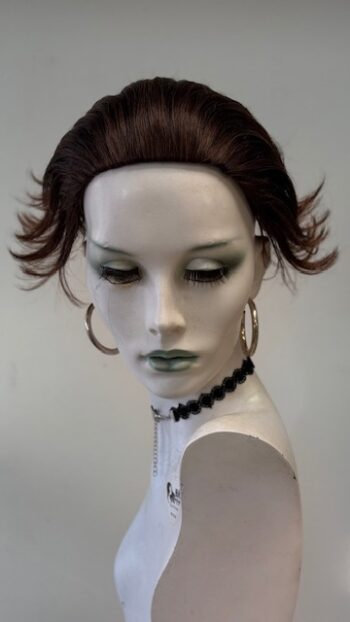 A mannequin with green lipstick and black jewelry.