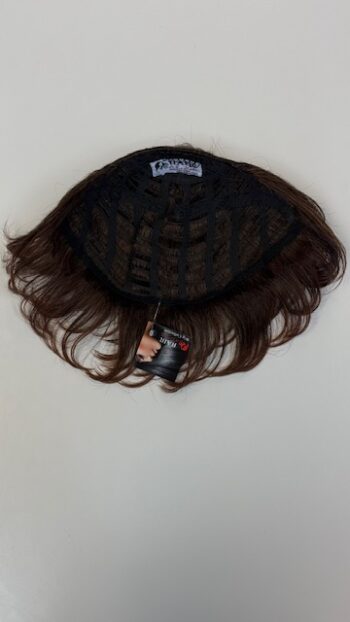 A wig hanging on the wall with a tag attached.