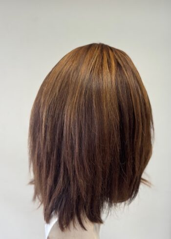 A woman 's head with long brown hair in front of a white wall.