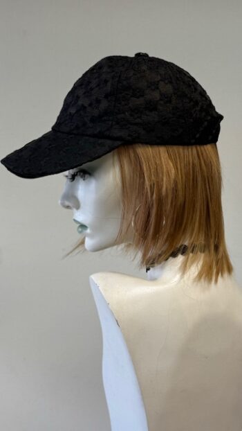 A mannequin wearing a black hat and a white wig.