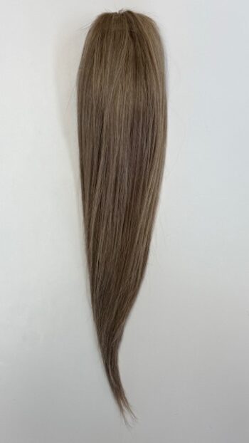 A long brown hair extension hanging on the wall.