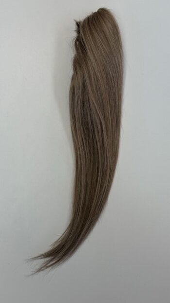 A long brown hair extension is hanging on the wall.