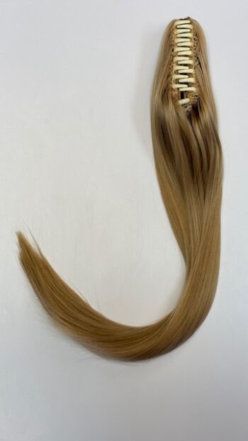 A long blond hair extension laying on top of a white table.