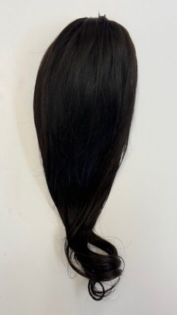 A black hair extension is hanging on the wall.