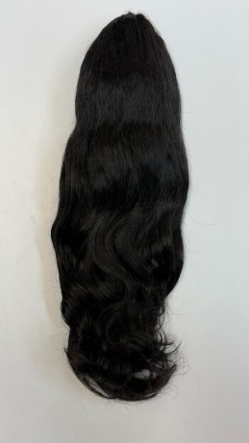 A black hair extension is laying on the floor.