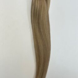 A blonde hair extension is hanging up on the wall.