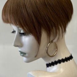 A mannequin with short hair and black jewelry.