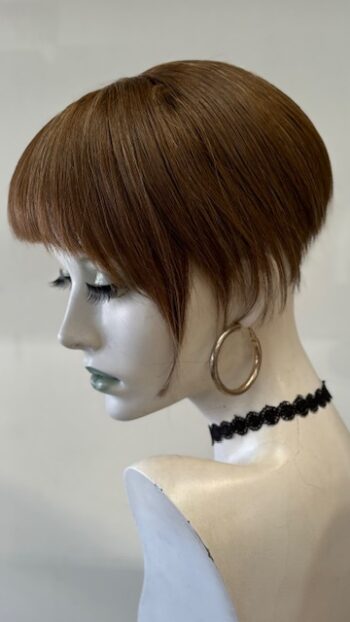 A mannequin with short hair and black jewelry.