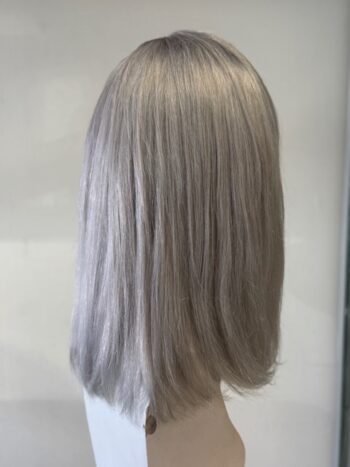 A woman with long gray hair is standing in front of a mirror.