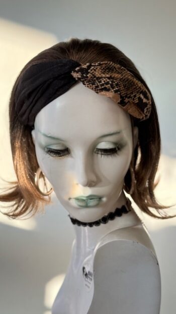 A mannequin with a snake head band on her head.