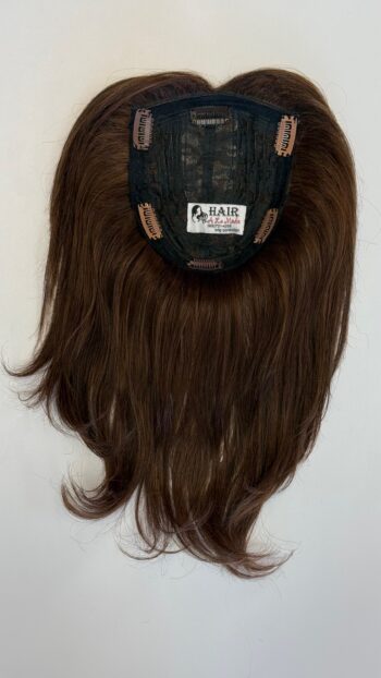 A brown wig with long hair hanging on the wall.