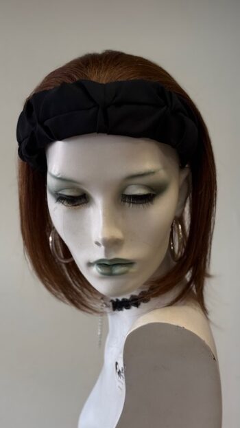 A mannequin wearing a black hat and earrings.