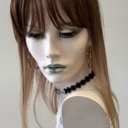 A mannequin with long hair and black jewelry.